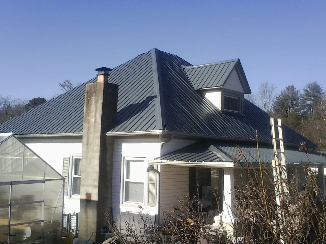 Dark blue standing seam metal roof on a white farmhouse with dormer — Slate & Tile Roof Repair by Roofing Brothers in Tiller