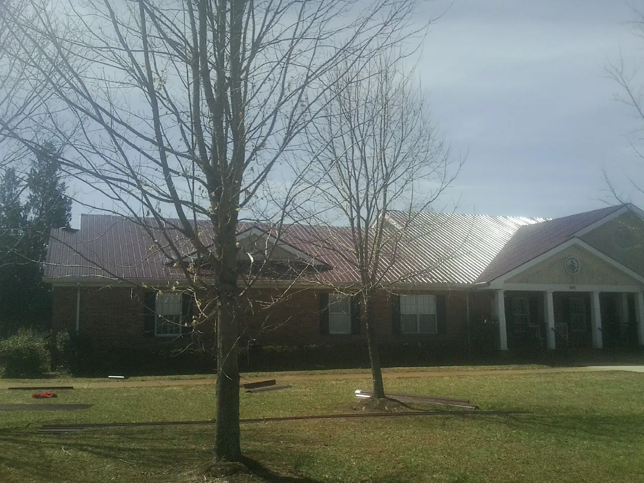 Red metal roof on a brick building seen from the front lawn in Tiller