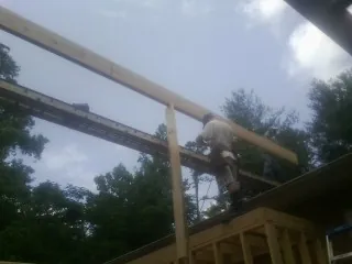 Carpenter setting a ridge beam over a new addition frame — Ice Dam Removal by Roofing Brothers in Tiller