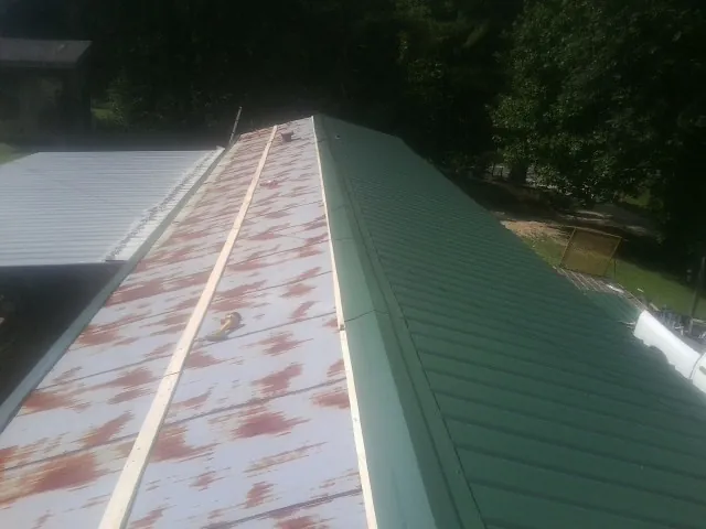 Old rusted panels beside newly installed green metal roofing — Wind Damage Roof Repair by Roofing Brothers in Tiller