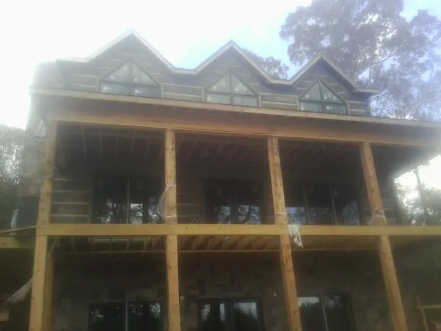 Dormers and porch framing on a large log home under construction — Roof Coating work by our crew in Tiller