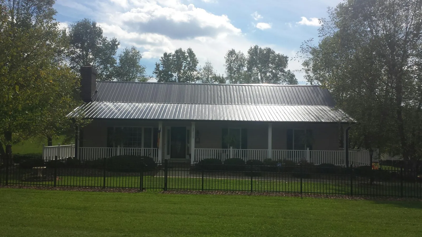 Gray metal roof on a brick ranch with a full width front porch — Gutter Guard Installation work by our crew in Tiller