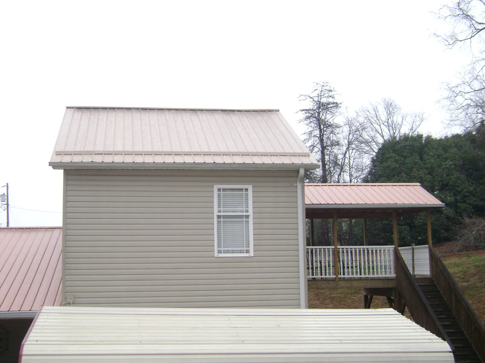 Tan metal roofs on a two story addition and attached porch, from a Roof Replacement job in Tiller